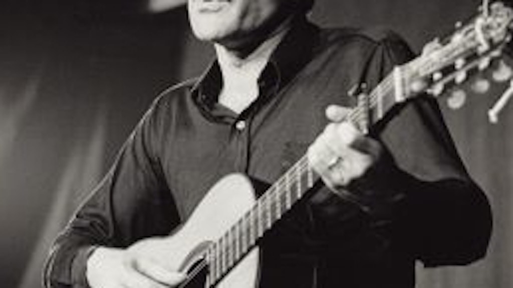 Porträt von Mani Matter, der auf einer Bühne Gitarre spielt und singt