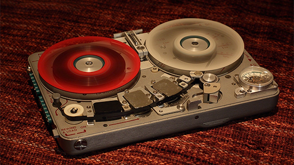 Vue en plongée d’un magnétophone espion avec une bobine rouge et une bobine grise.
