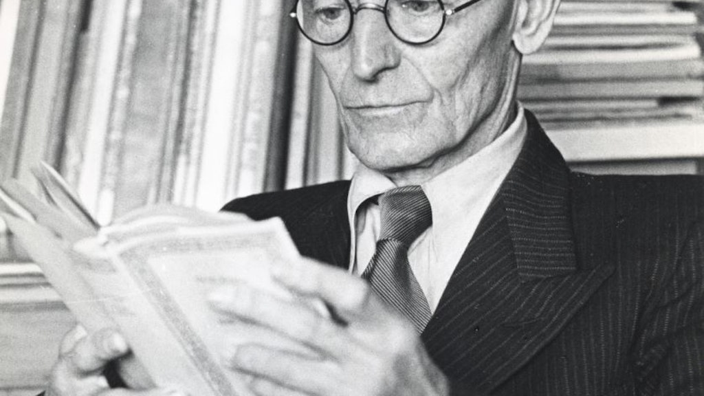 Hermann Hesse devant une bibliothèque, pensif, plongé dans un livre.