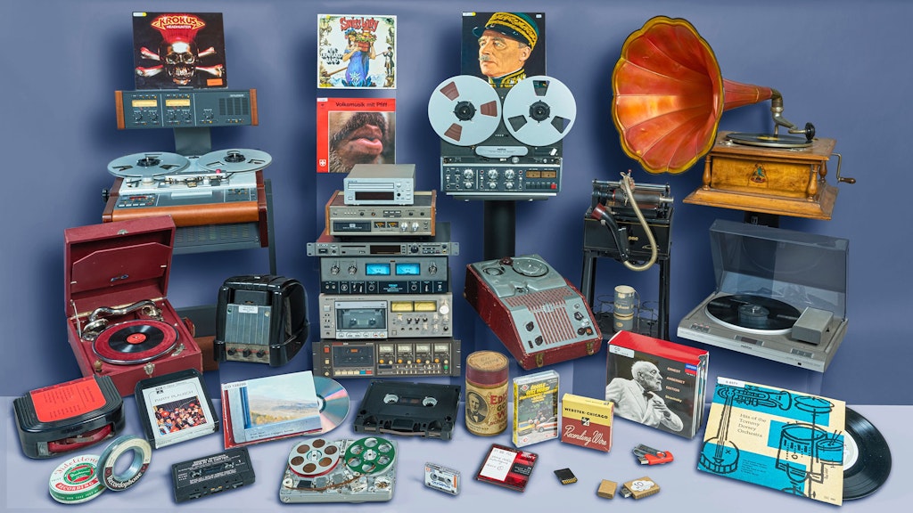 Quelques-uns parmi les nombreux exemplaires de différents supports sonores (disques, cassettes, cylindres, bandes magnétiques, fils magnétiques, etc.) de la Phonothèque nationale suisse.