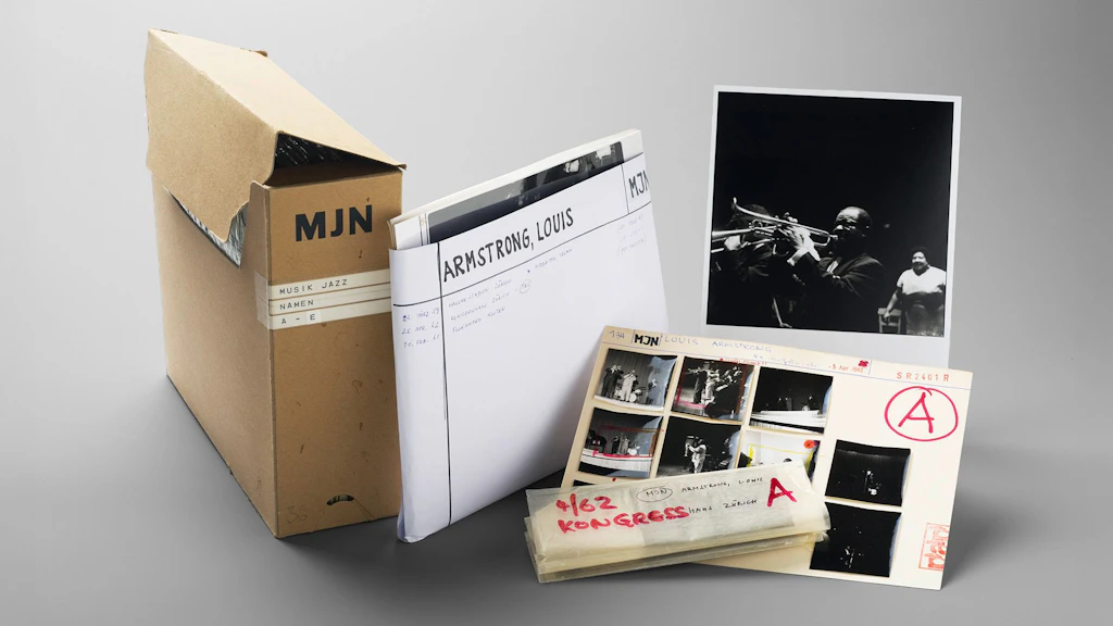 Originalschachtel mit Dokumenten aus dem Archiv von Niklaus Stauss, daneben Fotos und Negative auf einem Tisch.