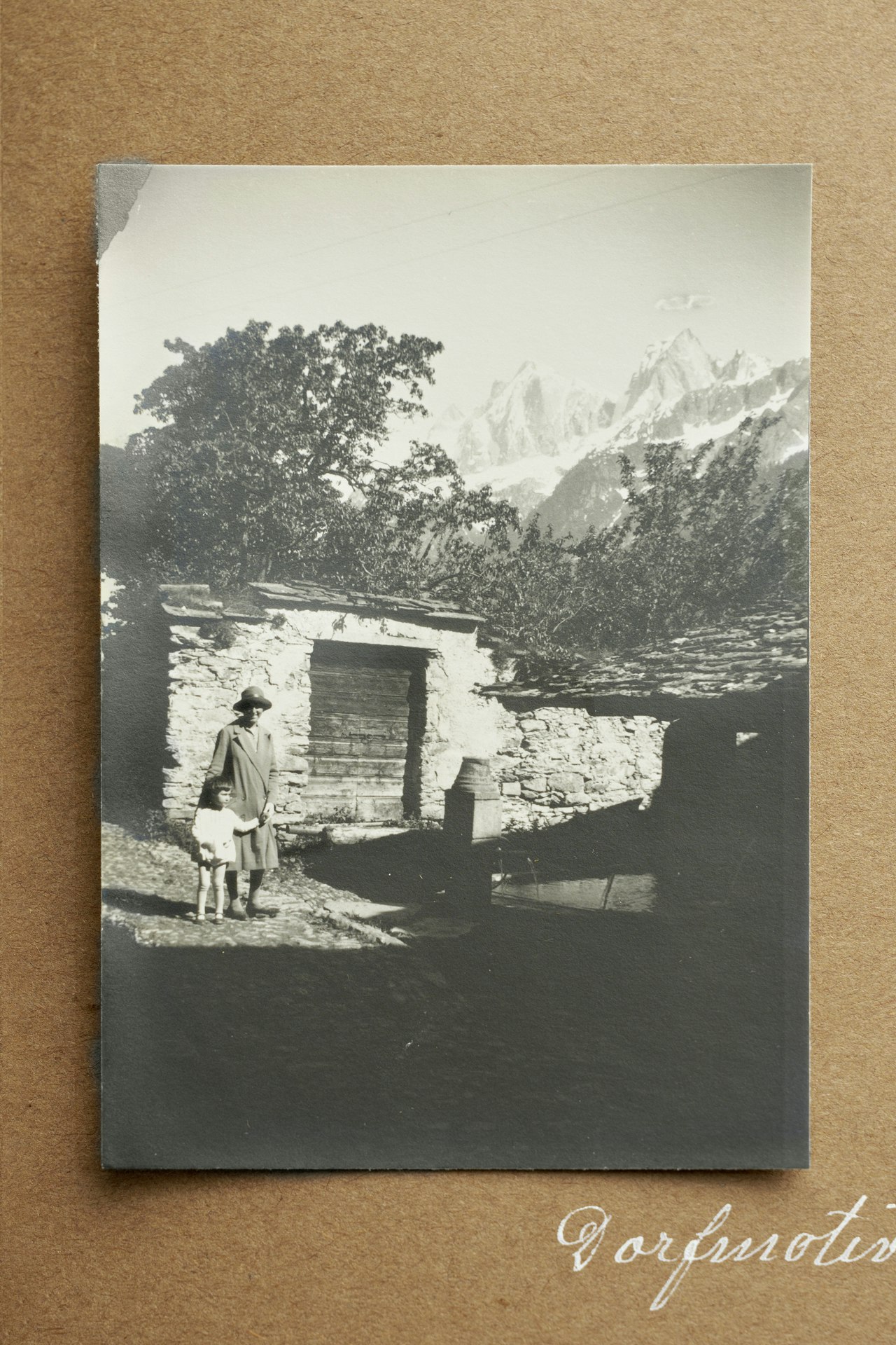 Ausschnitt aus dem besprochenen Fotoalbum, Seite mit Dorfmotiven zu Soglio. Auf der abgebildeten Fotografie sind zwei Personen und ein Waschhaus auszumachen.