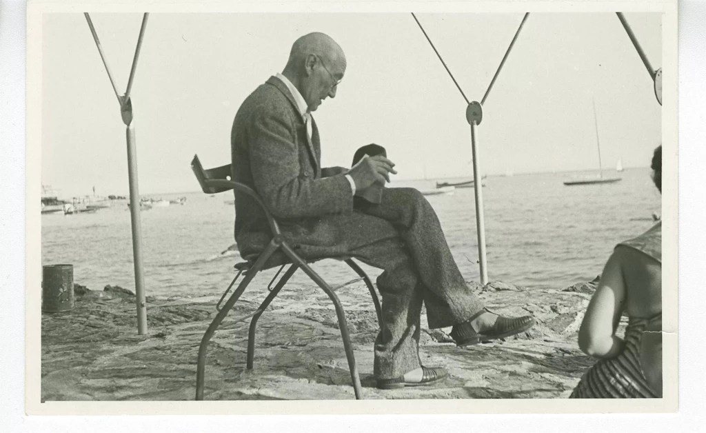 André Gide, avec lunettes, lisant sur une plage à Rapallo (Italie), en juillet 1950. Image provenant du Fonds André Gide des Archives littéraires suisses, Berne.