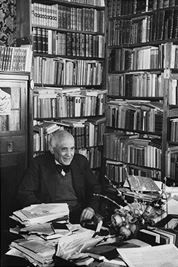 Ein freundlich lächelnder Jonas Fränkel am Schreibtisch in seiner Bibliothek im Jahr 1948, fotografiert von Margit Schildhauser.