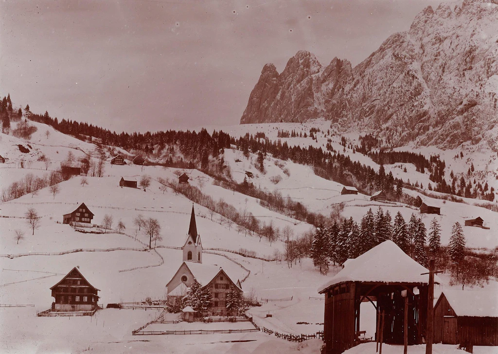 Dorfansicht von Innerthal, Kanton Schwyz, mit Pfarrkirche und überdeckter Holzbrücke, vor 1920. 