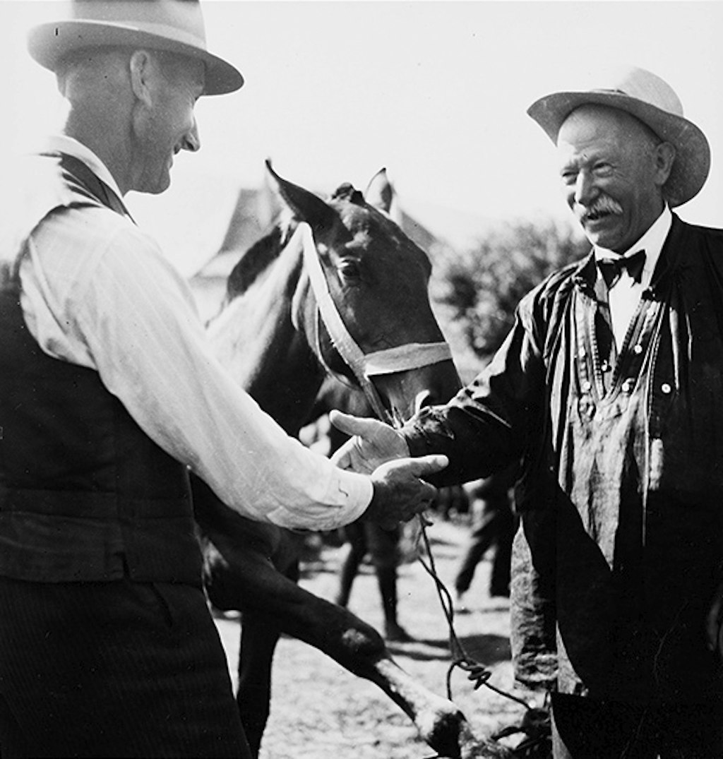 A man trots a horse in hand next to a group of men.