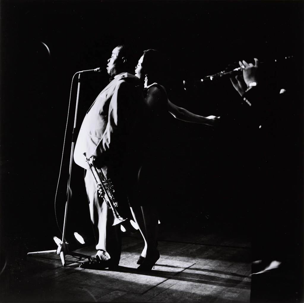 Louis Armstrong and the singer Jewel Brown at the microphone, profile view