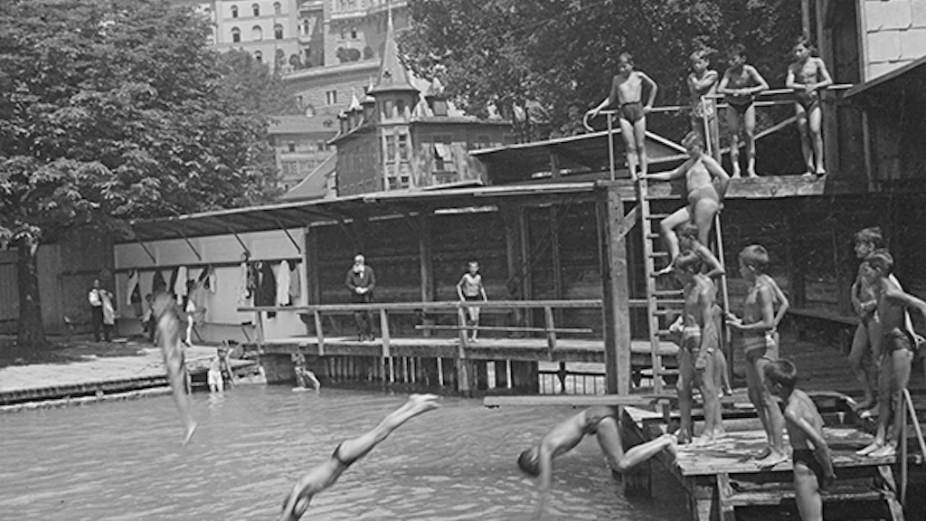 Depiction of three boys at the Marzili open-air bath. They are simultaneously jumping off two diving boards at the edge of the bath in a tributary of the Aare River. Other boys and an older man look on with interest.
