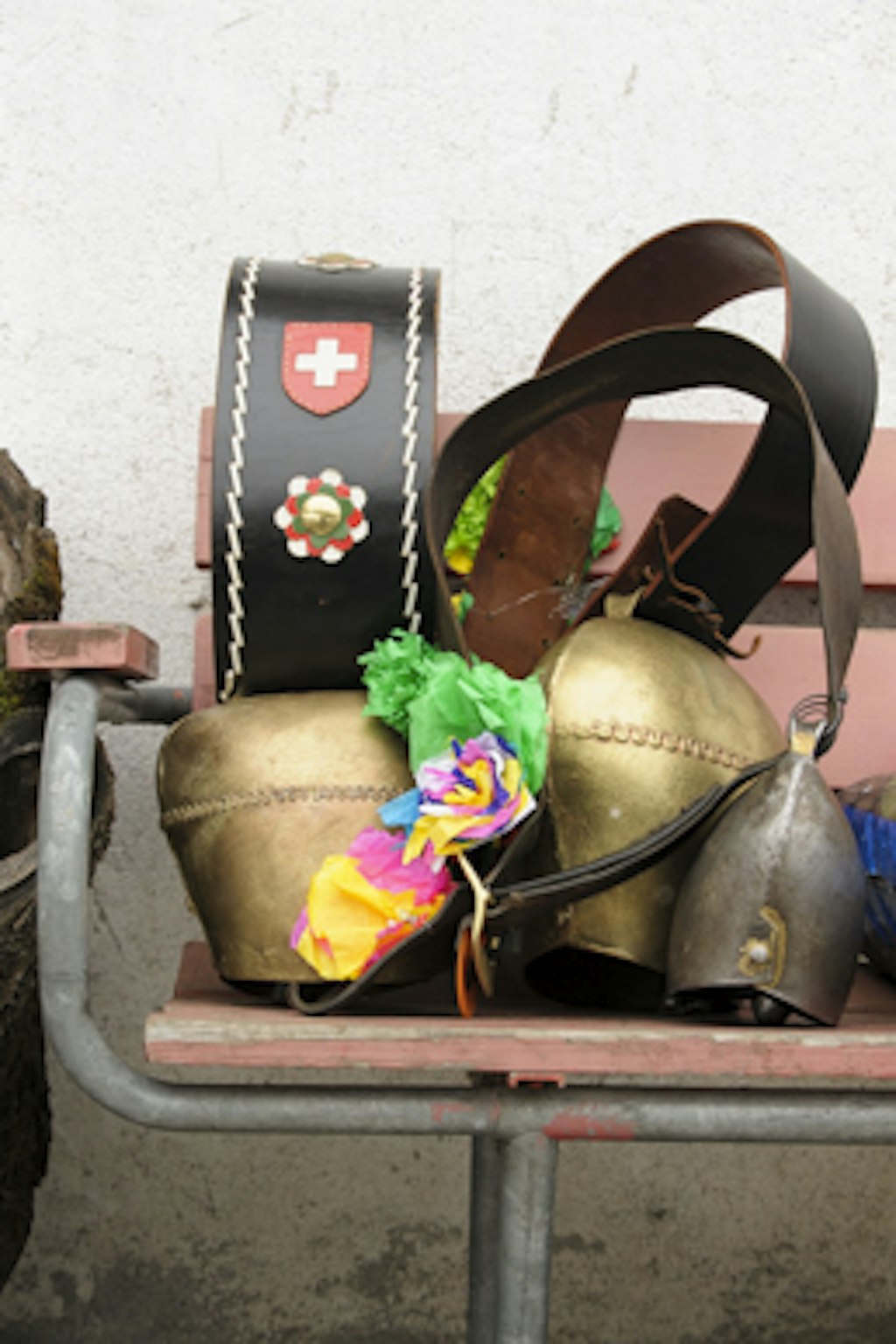 The picture shows three cowbells decorated with coloured flowers made of crepe paper.