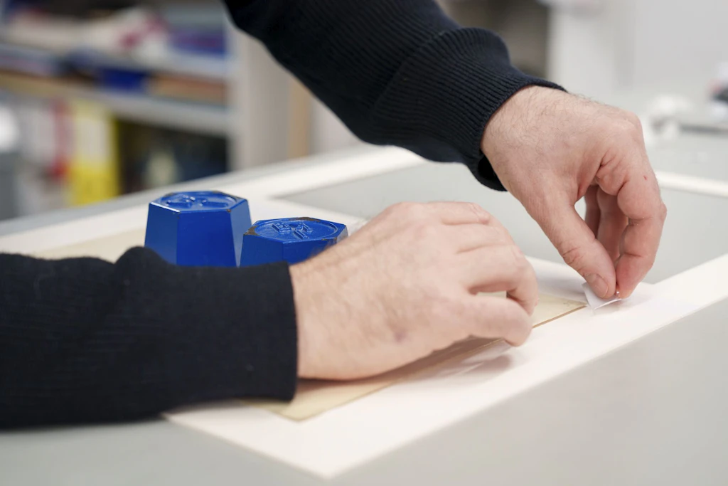 A National Library team member attaches the watercolour to its mount.