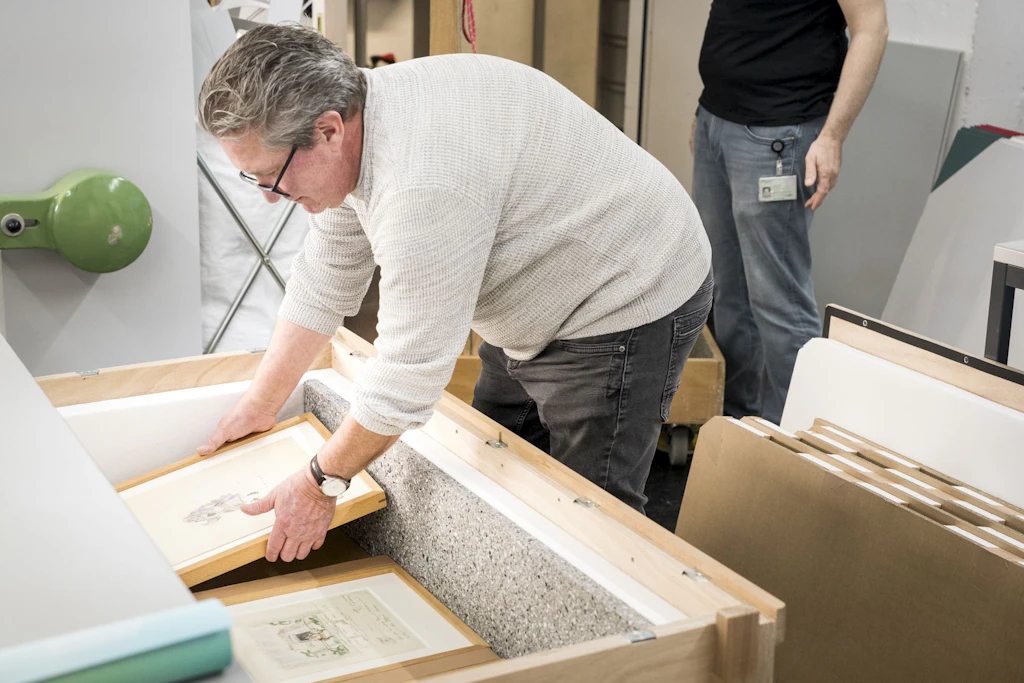 A National Library staff member places the framed artwork into its transport crate.
