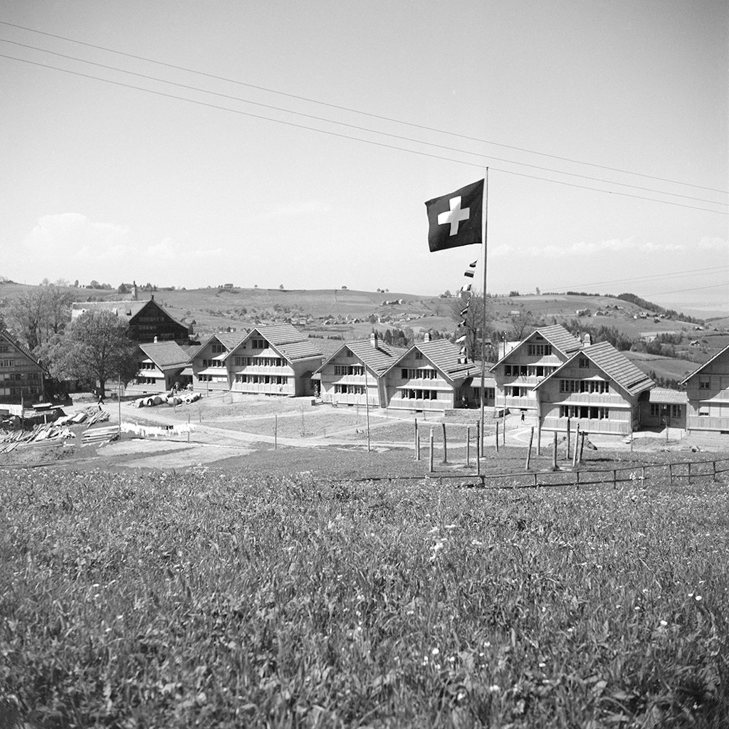 Le village d’enfants Pestalozzi avec ses bâtisses appenzelloises typiques et, au premier plan, un drapeau suisse hissé.