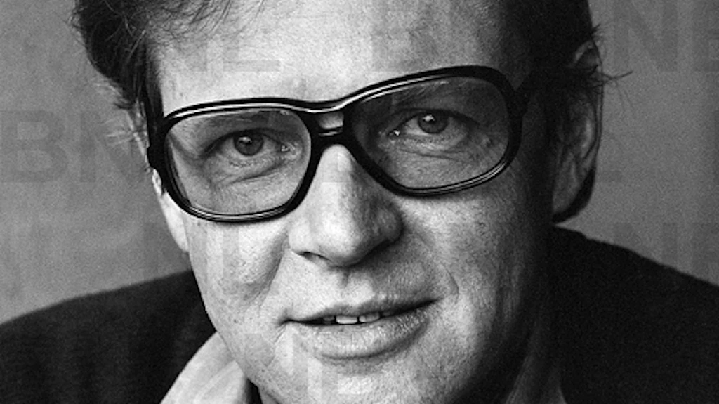 Portrait d’Otto F. Walter portant des lunettes et un pull-over foncé sur une chemise claire