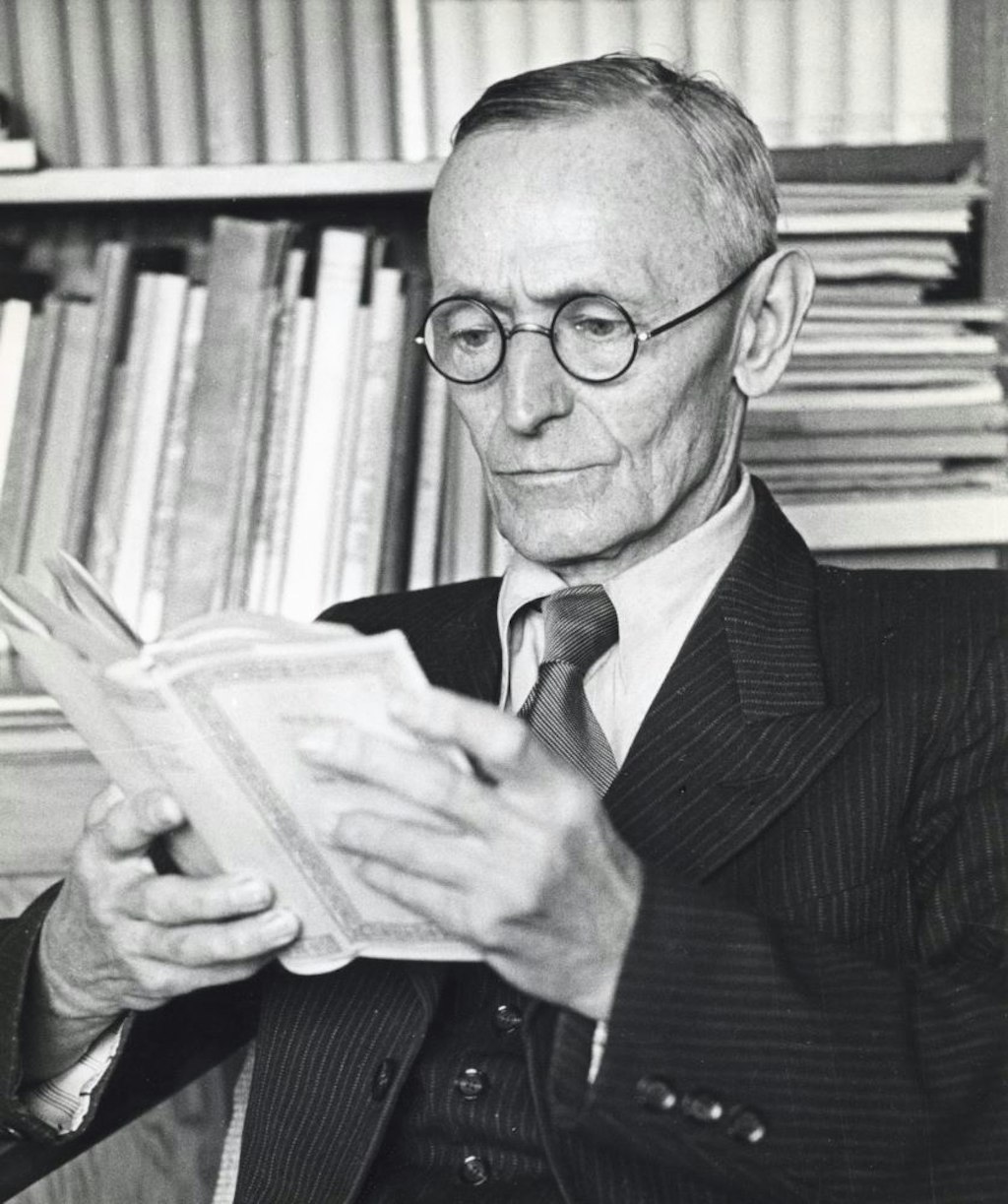 Hermann Hesse davanti alla libreria, pensieroso e immerso nella lettura.