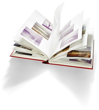 Aufgeschlagenes Fotoalbum, die Seiten sind aufgefächert. Fotografien von Landschaften.