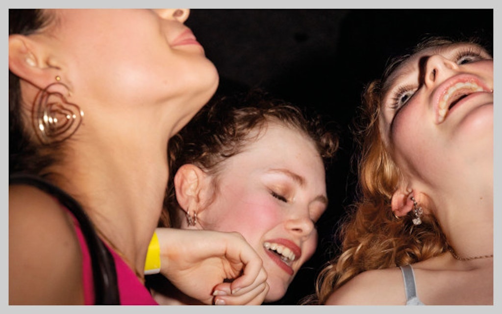 Fotografia di tre giovani donne che festeggiano in modo vivace.