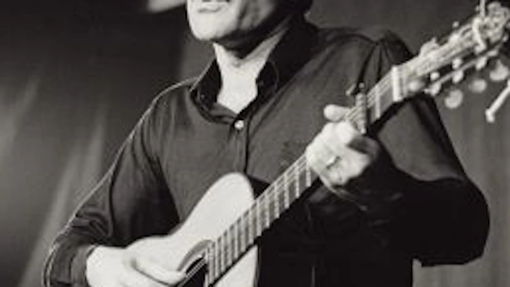 Porträt von Mani Matter, der auf einer Bühne Gitarre spielt und singt